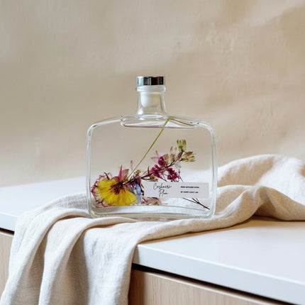 Urbn-cart handmade botanical reed diffuser with dried flowers in a clear glass bottle, silver cap, and a label reading "Cashmere Plum".