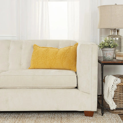 Urbn-cart yellow lumbar pillow with embroidered botanical pattern and frayed edge on a cream sofa.